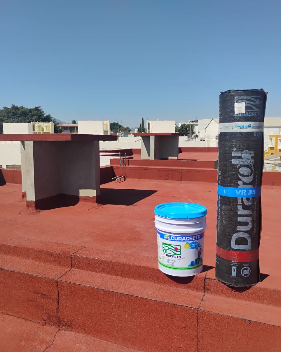 Azotea con pretiles impermeabilizados y rollos de manto en obra